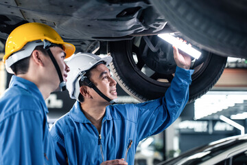Asian two automotive mechanic men wear helmet work in mechanics garage
