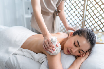Obraz na płótnie Canvas Asian beautiful woman enjoy thai hot compress massage with herbal bags