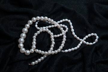 White pearls on the black shiny fabric background