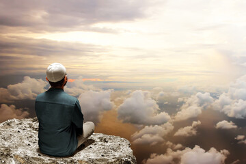 Muslim man sitting on top mountain