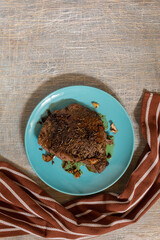 juicy steak with blood fried in a pan, top view, traditional food