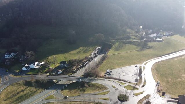 North entrance of subsea tunnel Mastrafjordtunnel along E39 coastal road Norway - Sunny day aerial showing entrance and road disappearing down into ground