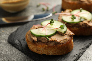 Slices of bread with delicious pate, cucumber and microgreens on grey table, closeup