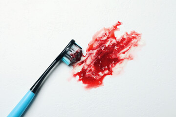 Toothbrush with paste and blood on white table, top view. Gum inflammation
