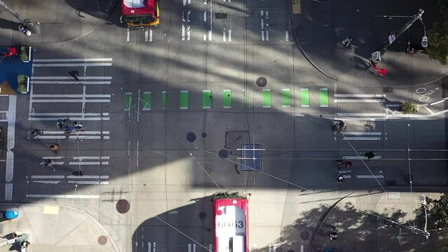 Straight down aerial shot of buses driving through a Seattle intersection with pedestrians on the outer crosswalks.