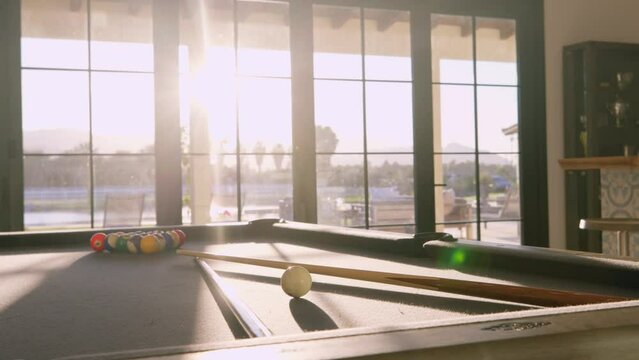 Pool table in vacation house with sunset behind windows in background