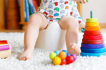 Closeup of cute little 12 months old toddler baby girl child sitting on potty.