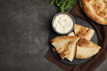 Cut pita bread, cream cheese and parsley on grey table, flat lay. Space for text