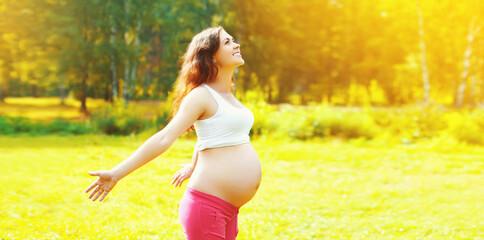 Happy smiling young pregnant woman enjoying in sunny summer day