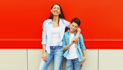 Portrait of happy smiling mother with son teenager on an orange background