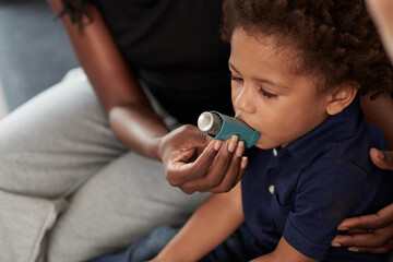 Mother helping little son to use asthma inhaler against allergic attack - obrazy, fototapety, plakaty