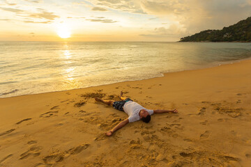 A relaxed man enjoys a beautiful sunset on a tropical island. Happy vacation concept
