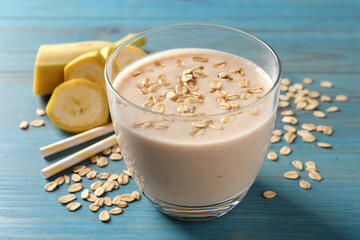 Glass of tasty banana smoothie with oatmeal on light blue wooden table