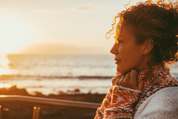 Enjoyed and serene lady dreaming and thinking outdoor with ocean beach and sunset light in...