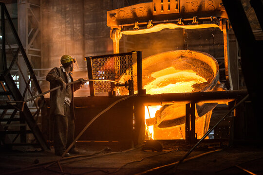 Steelworker at work near the tanks with hot metal