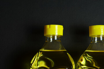 Sunflower cooking oil in a plastic bottle, black background.