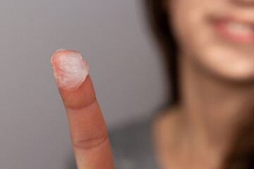 Closeup of a woman applying petroleum jelly to her face. Concept of slugging and skin care for dry,...