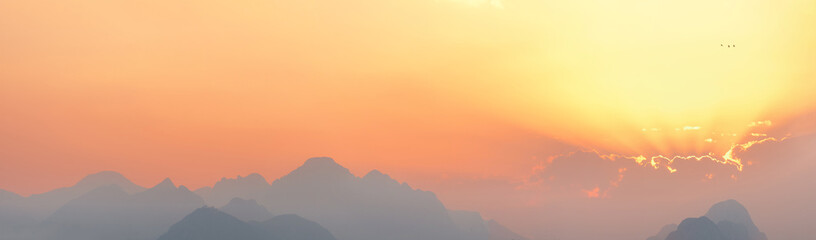 bright sunset or sunrise sky with misty mountains