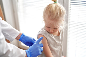 Arm of caucasian elementary age disinfected by the doctor right before the vaccination