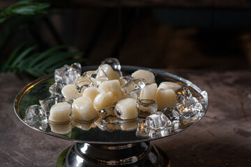 Fresh sea scallops among ice on a copper tray in a dark room