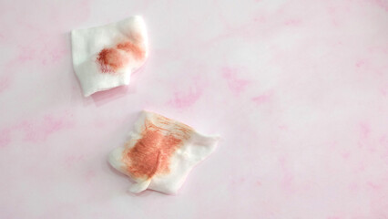 Two pieces of cotton pads with red stain from wiping off lipstick. With copy space on the right.