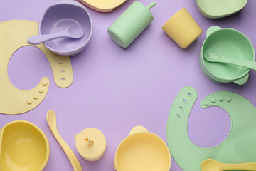 Flat lay composition with baby feeding accessories and bib on violet background, space for text