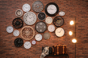 Collection of clocks hanging on red brick wall indoors