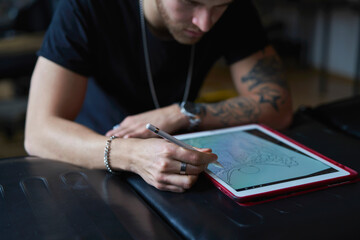 Caucasian tattoo artist  designing motifs on digital tablet