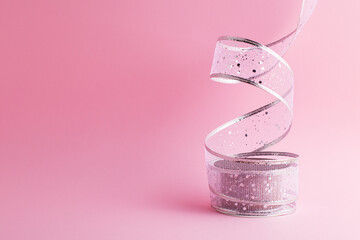 Front view of festive celebration decorative beautiful sparkly delicate lace ribbon isolated on pastel pink background with copy space. Greeting concept.