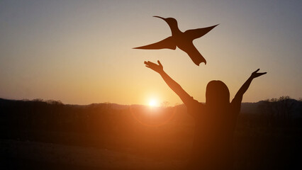 A man with a cross at sunset, a golden light beneath a flying bird, indicates the joy of freedom...