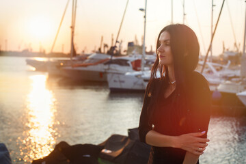 Silhouette sunset with water view and a woman shadow standing on the port. Golden sky at dusk