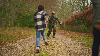 American soldier coming home on leave kneels to meet son and daughter who run to greet him outdoors - shot in slow motion
