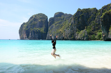Fototapeta na wymiar female tourist jumping at Maya Bay on Phi Phi Islands, Thailand