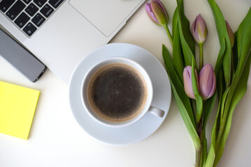 Home office desk with laptop, smartphone, pink tulips and cup of coffee on white table. Flat lay Business workplace. Top view. laptop for businesswoman 