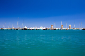 Obraz premium Rhodes Windmills in the Mandraki harbor and marina. Sightseeing in the old town. Rhodes, Greece
