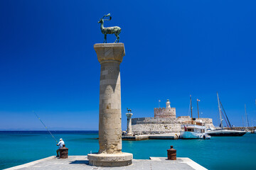 Entrance to Mandraki harbor and marina. Hirsch and Hirschkuh, Elafos and Elafina, bronze statues of deer and stags in the place of the Colossus of Rhodes. Sightseeing in the old town. Rhodes, Greece - obrazy, fototapety, plakaty