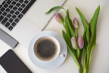 Home office desk with laptop, smartphone, pink tulips and cup of coffee on white table. Flat lay Business workplace. Top view. laptop for businesswoman 