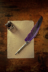 A quill pen with a vintage ink well and a piece of old paper, overhead flat lay shot