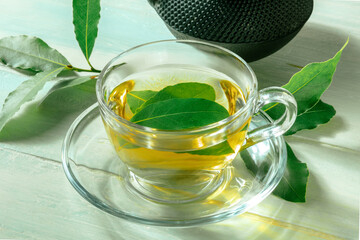 Bay leaf tea. Fresh laurel leaves infusion with a cup and a teapot, on a rustic wooden background