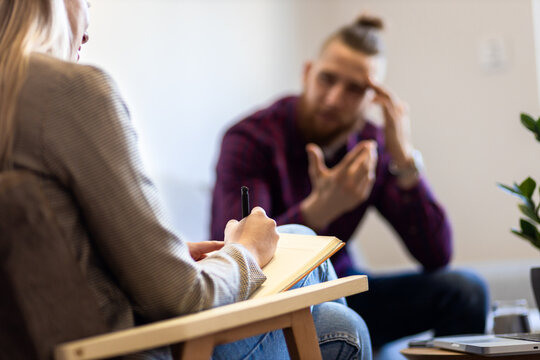 Young man talking to female psychologist during session.