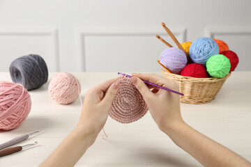 Woman crocheting with pink thread at white wooden table, closeup