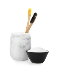 Fototapeta na wymiar Bamboo toothbrushes in holder and bowl with baking soda on white background