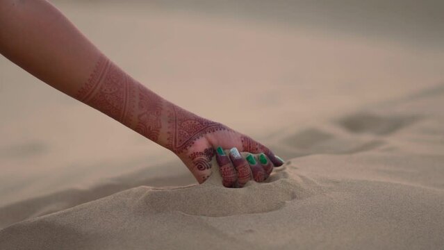Closeup shot of hands of an Indian female lifting and pouring sand of the desert at Sam Sand dunes in Thar Desert Jaisalmer, Rajasthan, India. Female pouring sand in the desert.