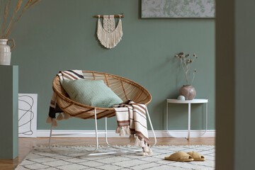 Stylish composition of creative and cozy living room interior with coffee table, rattan armchair, plants, carpet and beautiful boho accessories. Green walls and parquet floor. Copy space. Template..