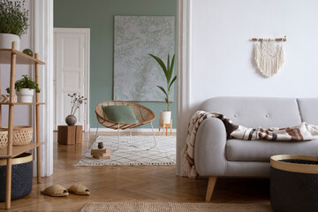 Creative living room interior design composition with crey scandi sofa, rattan armchair, plants, carpet and beautiful boho accessories. Eucalyptus walls and parquet floor.