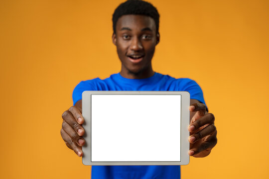 African american man showing blank digital tablet screen with copy space in yellow studio.