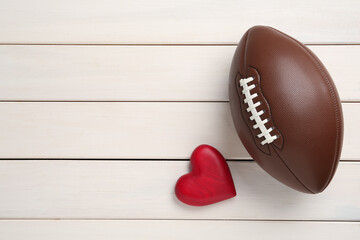 American football ball and heart on white wooden background, flat lay. Space for text