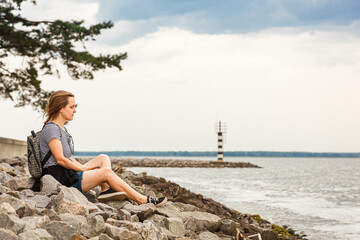 Beautiful girl on the sea overlooking the lighthouse and blue sky with clouds