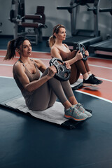 Fototapeta na wymiar Pretty women working out in a gym. Adult ladies with beautiful shaped bodies.