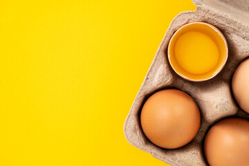 Fresh brown chicken eggs isolated on yellow table background.
